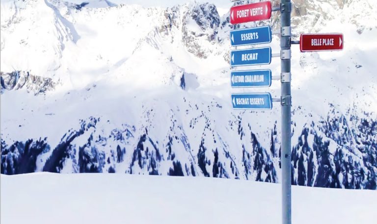 A snowy mountain landscape with a signpost showing directions to various locations, including 