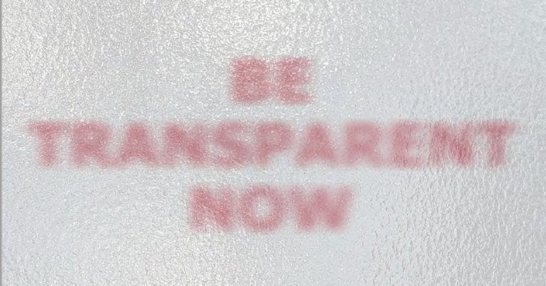 Blurred red text on a textured white background reads "BE TRANSPARENT NOW.