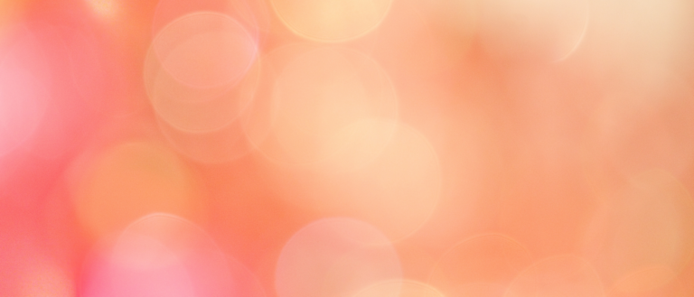 A soft, out-of-focus bokeh background with warm hues of orange, pink, and peach. The image features circular light spots, creating a dreamy and abstract visual effect.