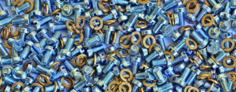 A large assortment of blue metallic screws mixed with yellow washers, scattered randomly. The screws appear shiny and have hexagonal heads. The image emphasizes the contrast between the blue screws and yellow washers.