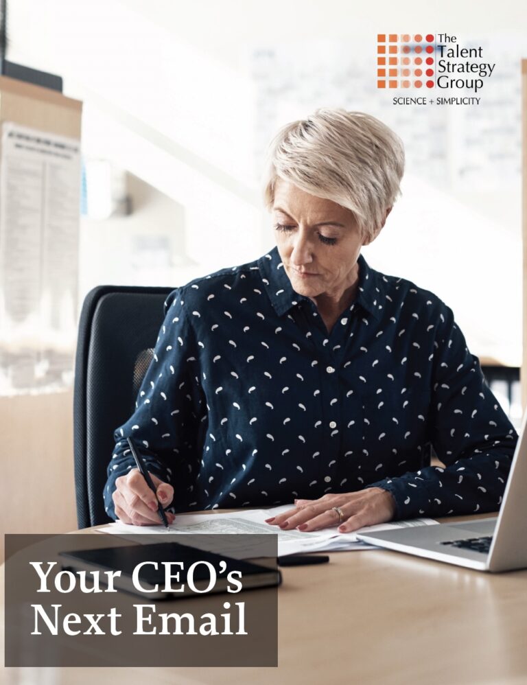 A woman with short gray hair sits at a desk, writing on paper with a pen. Office supplies and documents are on the desk. The text reads "Your CEO’s Next Email" with The Talent Strategy Group logo in the corner.